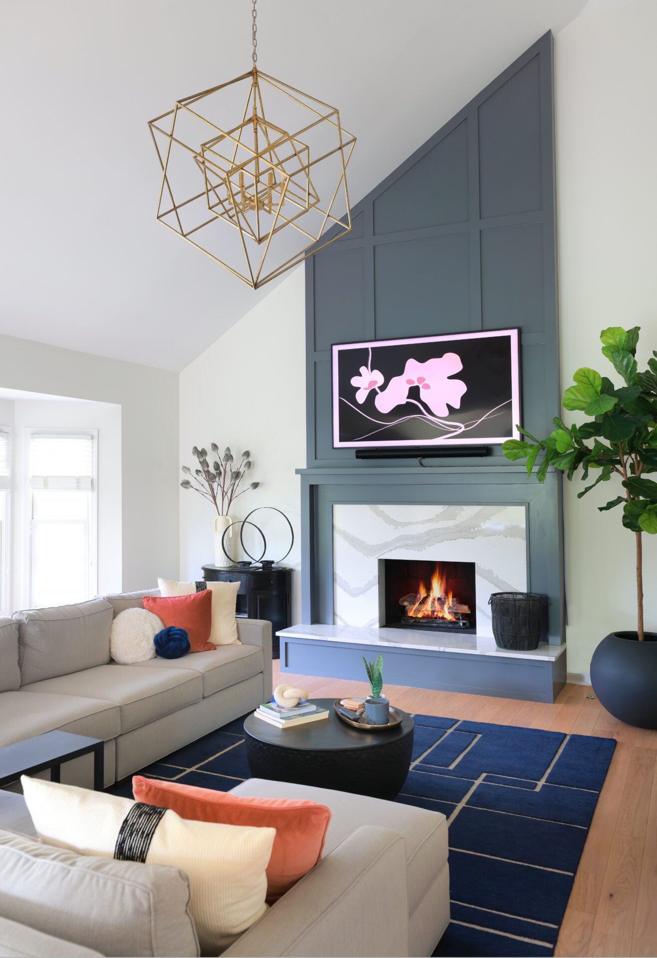 White cathedral ceiling with blue-gray wainscoting above fireplace reaching to ceiling, gold chandelier